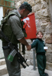March 21, 2005- A Palestinian boy (right) shakes the hand of Israeli border police officer Amal at the entrance of the Ibraheemi (Abraham) mosque in the West Bank city of al-Khalil (Hebron)- Photo by; Nayef Hashlamoun.